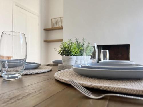 a table with plates and a glass of water on it at Wrightson House by Blue Skies Stays in Stockton-on-Tees