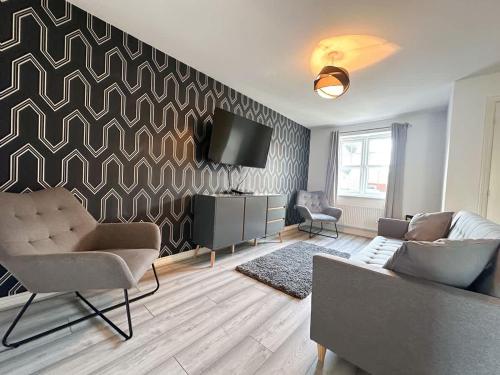 a living room with a couch and a tv on a wall at Coral House by Blue Skies Stays in Thornaby on Tees