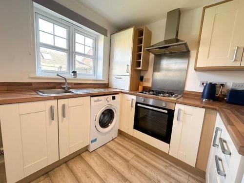 a kitchen with white cabinets and a washer and dryer at Coral House by Blue Skies Stays in Thornaby on Tees