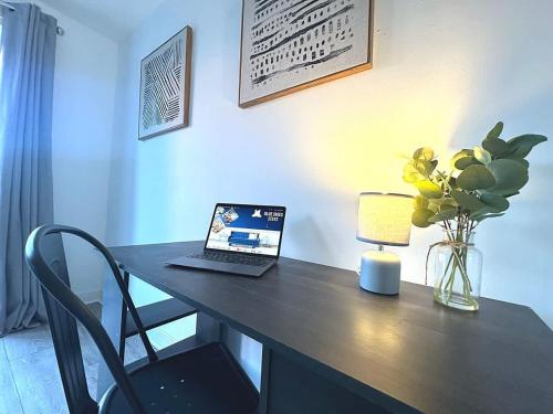 a desk with a laptop and a vase of flowers at Alma House by Blue Skies Stays in Hartlepool