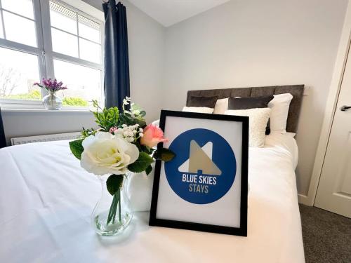a vase of flowers on a table with a sign on a bed at Letchworth House by Blue Skies Stays in Stockton-on-Tees