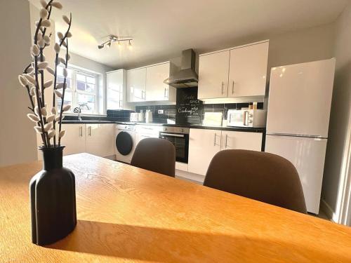 a kitchen with a wooden table with chairs and a vase at Letchworth House by Blue Skies Stays in Stockton-on-Tees