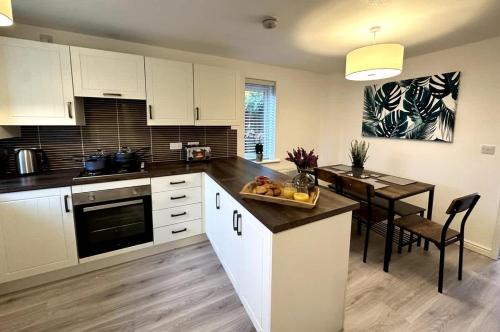 a kitchen with white cabinets and a dining table at Middlebeck House by Blue Skies Stays in Middlesbrough