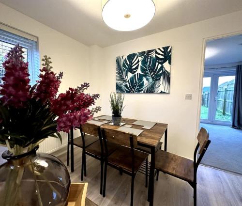 a dining room with a table and a vase with flowers at Middlebeck House by Blue Skies Stays in Middlesbrough