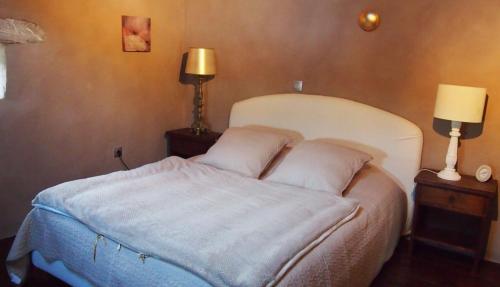 - une chambre avec un lit blanc et 2 lampes dans l'établissement Gîte rurale, très beau pigeonnier avec vue, à La Celle-sous-Gouzon