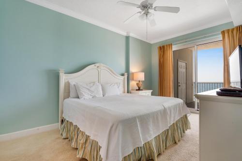 Un dormitorio con una cama blanca con ventilador de techo. en Island Royale 703, en Gulf Shores