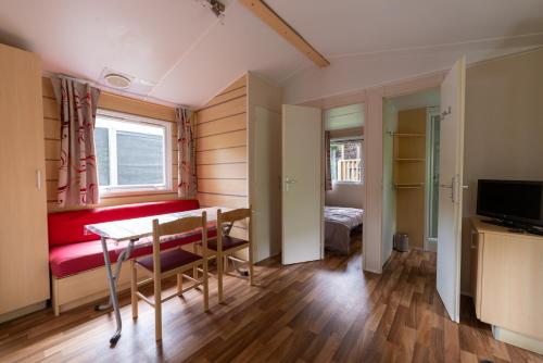 Cette petite chambre comprend une table et un canapé rouge. dans l'établissement Camping Le Barutel, à Meyras