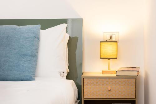 a bed with a blue pillow and a lamp on a night stand at Vicolo Trevi Apartment by Rental in Rome in Rome