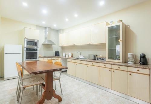 a large kitchen with a wooden table and a table and chairs at Quinta dos Arcos in Barcelos