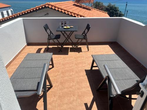 a patio with a table and chairs on a balcony at Gori House in Madalena do Mar