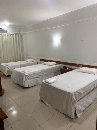 three beds in a room with white walls at Hotel Eduardus in Palmas