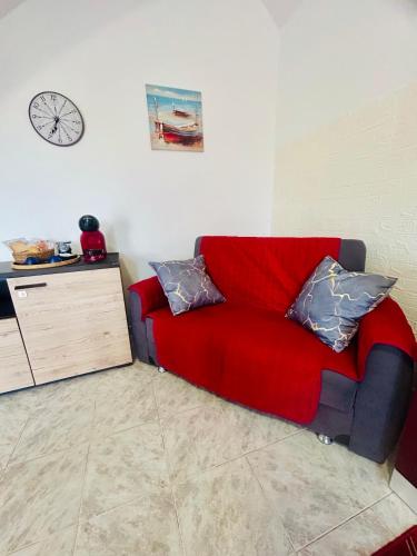 a red couch in a room with a clock on the wall at Podere 48 - Relax tra mare e natura a Sabaudia - fino a 5 persone in San Donato