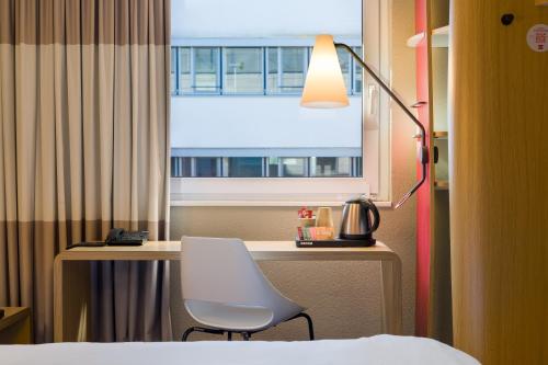 a room with a desk with a chair and a window at ibis Hotel Hamburg St. Pauli Messe in Hamburg