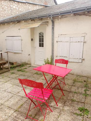 deux chaises rouges et une table rose devant une maison dans l'établissement L Ecrin Amboisien, à Amboise