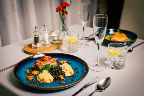 a table with two plates of food and wine glasses at Hotel Bystrička in Martin