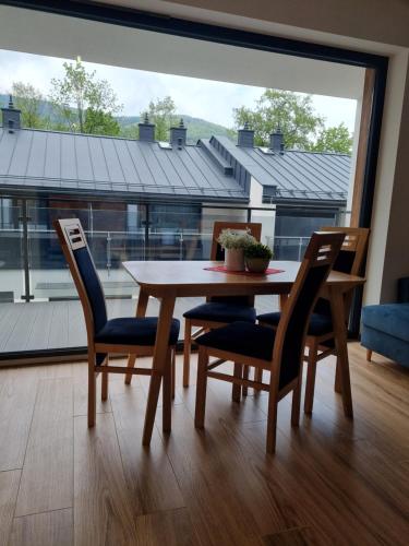 ein Tisch und Stühle in einem Raum mit einem großen Fenster in der Unterkunft Szczyrkowska Ostoja in Szczyrk