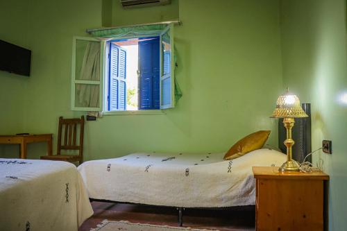 a green bedroom with two beds and a window at Auberge Souktana in Taliouine