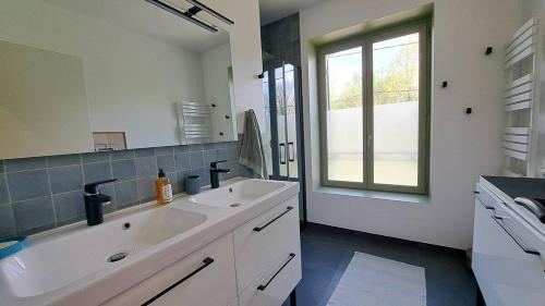 une salle de bain blanche avec un lavabo et une fenêtre dans l'établissement Le Quai de Mezos, à Mézos