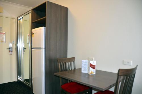 a kitchen with a table and a refrigerator at Hunts Hotel Liverpool in Liverpool