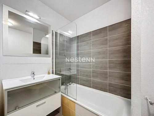 une salle de bain avec un lavabo, une baignoire et un miroir dans l'établissement 3692-T2 dans une résidence avec piscine, à Argelès-sur-Mer