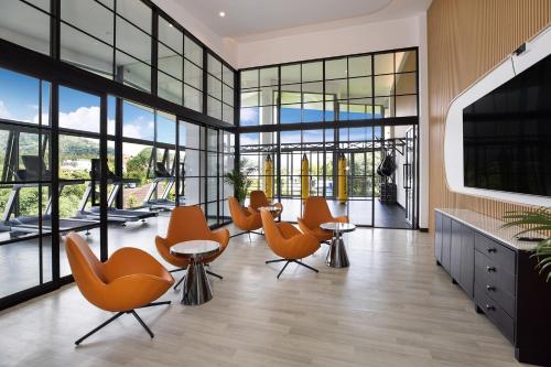 a lobby with orange chairs and tables and windows at Elite Atoll Serviced Apartments Phuket in Rawai Beach