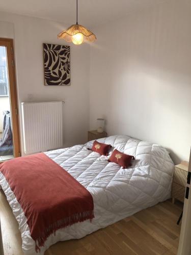 une chambre avec un lit blanc avec des oreillers rouges dans l'établissement Appartement T3 65 m2 2 chambres terrasse, à Aix-les-Bains