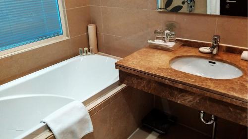 a bathroom with a sink and a bath tub at Holiday Inn Mudanjiang by IHG in Mudanjiang