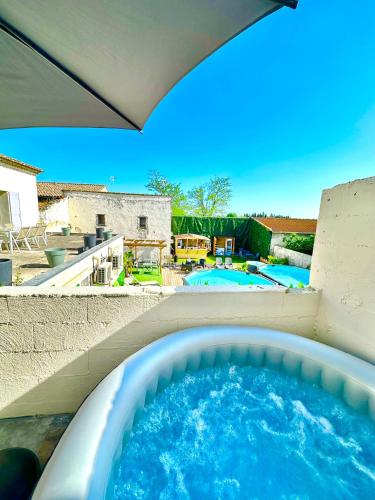 a hot tub in a backyard with a swimming pool at Les Appartements du Mas - Aventurine in Aigues-Mortes