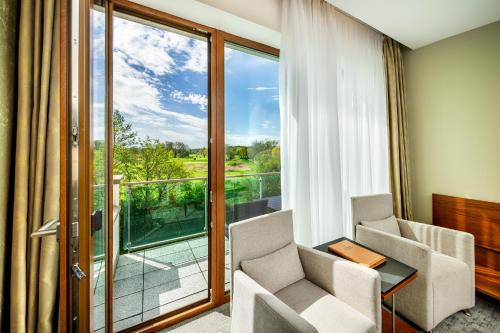 Pokój z 2 krzesłami i stołem oraz dużym oknem w obiekcie Wellness Hotel Diamant w mieście Hluboká nad Vltavou