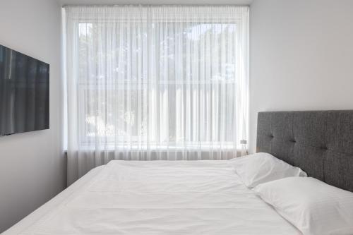 a bedroom with a white bed and a window at Roze Village Jūrnieka Ligzda in Pērkone