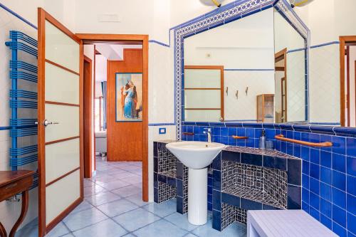 a blue tiled bathroom with a sink and a mirror at La casa dei desideri in Maiori