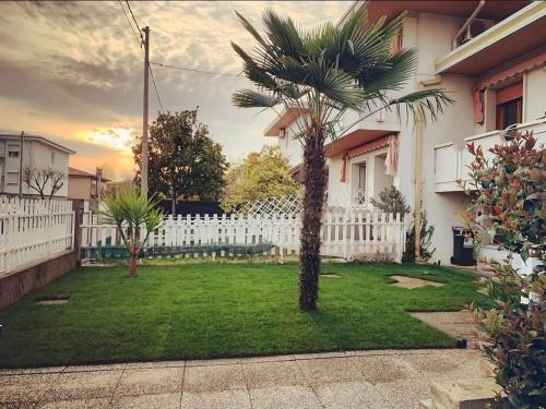 a palm tree in a yard next to a white fence at Venice Airport and Station Train Free Parking in Quarto dʼAltino