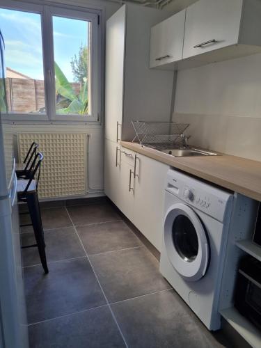 une cuisine avec une machine à laver et un évier dans l'établissement Le Bigourdan - 3 Chambres, à Tarbes