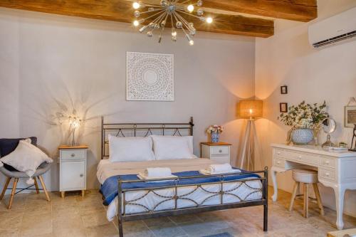 a bedroom with a bed and a desk and a chandelier at Gudja 2BR - A Home of Character in the Village Core in Gudja