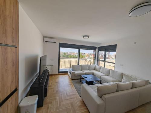 a living room with a couch and a tv at Airport sunset apartment in Ledine