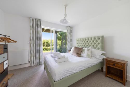 une chambre avec un grand lit et une fenêtre dans l'établissement NEW Bauhinia House Spa Access and Lakeside Home, à Somerford Keynes