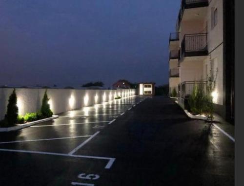 an empty parking lot with lights on the side of a building at Airport sunset apartment in Ledine