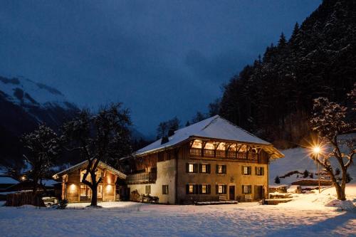 a large house in the snow at night at La Ferme du Lac Vert in Montriond