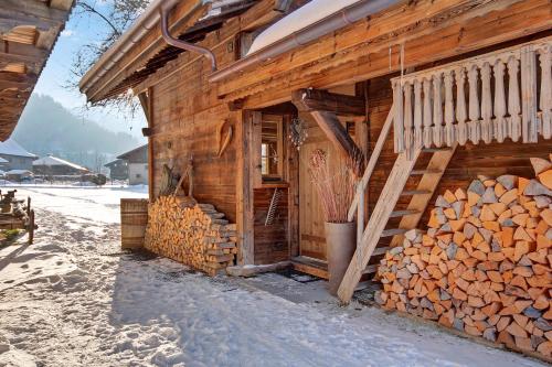 a wooden cabin with a pile of fire wood at La Ferme du Lac Vert in Montriond