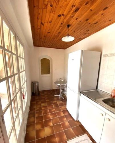 Il comprend une cuisine avec un réfrigérateur blanc et un plafond en bois. dans l'établissement Appartement Rez de Villa Terrasse Piscine Parking, à Hyères