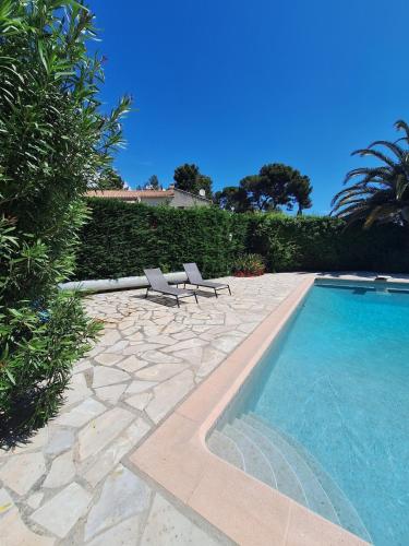 - une piscine avec 2 chaises longues à côté d'une haie dans l'établissement Appartement Rez de Villa Terrasse Piscine Parking, à Hyères