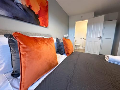 a bedroom with a bed with an orange pillow at Densham House by Blue Skies Stays in Stockton-on-Tees