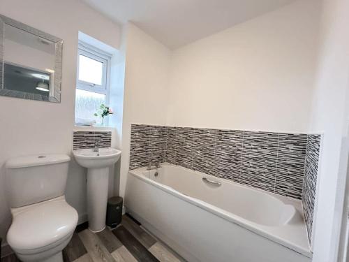 a bathroom with a toilet and a tub and a sink at Densham House by Blue Skies Stays in Stockton-on-Tees