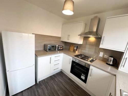 a kitchen with white cabinets and a stove top oven at Turnstile Place by Blue Skies Stays in Middlesbrough