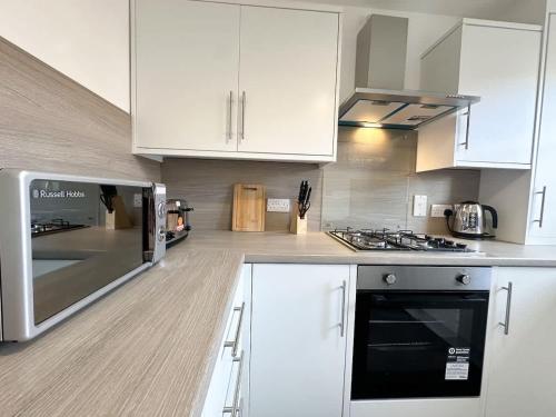 a kitchen with white cabinets and a stove top oven at Turnstile Place by Blue Skies Stays in Middlesbrough
