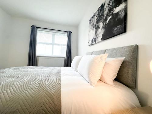 a bedroom with a bed with white sheets and a window at High Market Place by Blue Skies Stays in Ashington