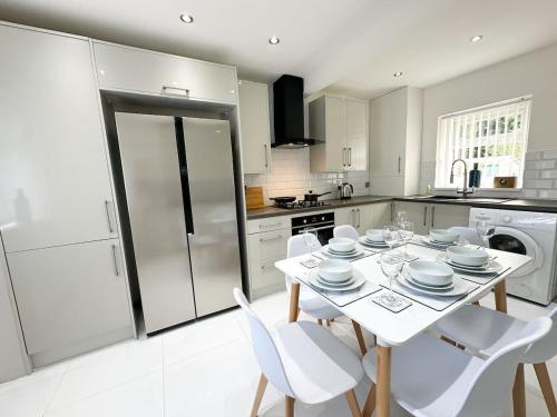 a kitchen with a white table and white chairs at Malvern House by Blue Skies Stays in Stockton-on-Tees