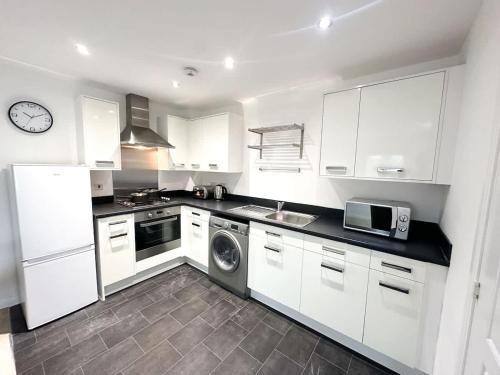a kitchen with white cabinets and a washer and dryer at Bourneville House by Blue Skies Stays in Stockton-on-Tees