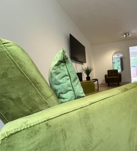 a living room with a green couch and a television at Anchorage Place by Blue Skies Stays in Thornaby on Tees