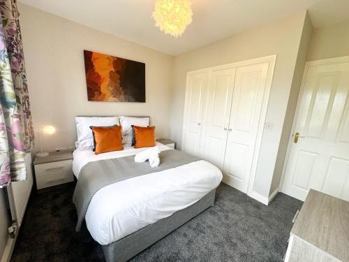 a bedroom with a large bed with orange pillows at Geranium House by Blue Skies Stays in Stockton-on-Tees